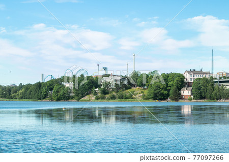 Toolo Bay in City Park, Helsinki, Finland. Across the water, rides at Linnamaki amusement park can be seen above the trees. Toolo Bay in City Park, Helsinki, Finland. Across the water, rides at Linnamaki amusement park can be seen above the trees. 77097266
