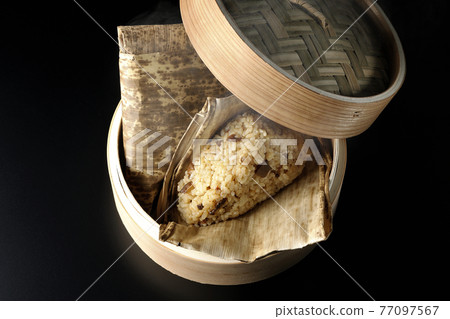 A picture of Chinese rice dumplings steamed in a bamboo steamer with a black background (overhead view) A picture of Chinese rice dumplings steamed in a bamboo steamer with a black background (overhead view) 77097567