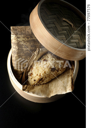 A picture of Chinese rice dumplings steamed in a bamboo steamer with a black background (overhead view) A picture of Chinese rice dumplings steamed in a bamboo steamer with a black background (overhead view) 77097576