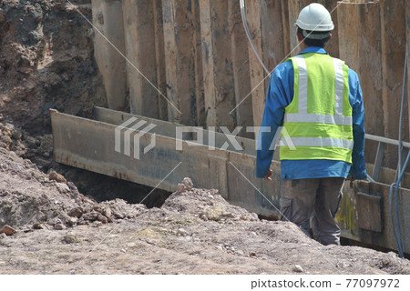 SEREMBAN, MALAYSIA -JANUARY 31, 2017: Construction workers working at the construction site during daytime. They are required to wear proper and suitable safety gear to ensure their safety. SEREMBAN, MALAYSIA -JANUARY 31, 2017: Construction workers working at the construction site during daytime. They are required to wear proper and suitable safety gear to ensure their safety. 77097972