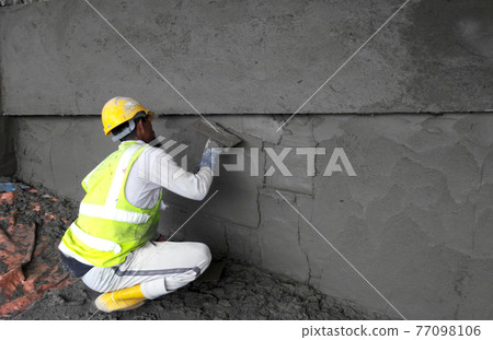 JASIN, MALAYSIA -JANUARY 14, 2017: Construction workers plastering building wall and beam using cement plaster mix of cement and sand at the construction site in Jasin, Malaysia 77098106