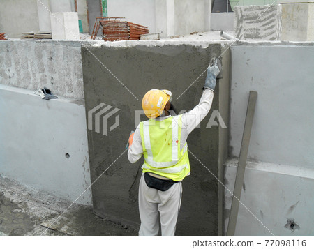 JASIN, MALAYSIA -JANUARY 14, 2017: Construction workers plastering building wall and beam using cement plaster mix of cement and sand at the construction site in Jasin, Malaysia 77098116