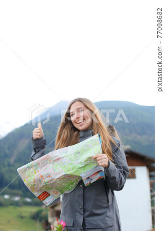 Caucasian girl looking at map in mountains and showing thumbs up. 77098682
