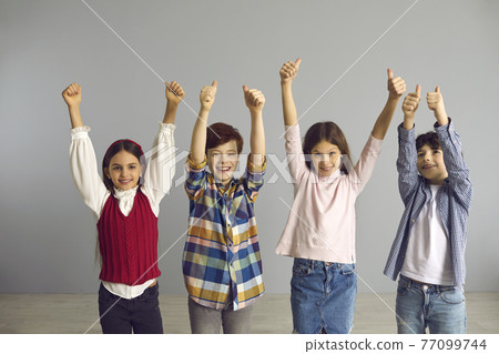 Energetic optimistic preteen children show hand up with thumbs up gesture Energetic optimistic preteen children show hand up with thumbs up gesture 77099744
