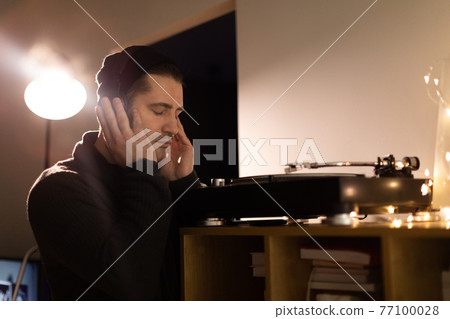 unshaven handsome millennial guy listens to music with headphones closed eyes 77100028