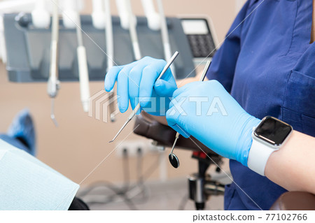 dental instruments in the hands of the doctor. Dentist in sterile latex gloves holding dental tools Close-up dental instruments in the hands of the doctor. Dentist in sterile latex gloves holding dental tools Close-up 77102766