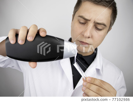 A lab technician examines a sample of shampoo he was given for analysis. Chemical analysis of the composition of detergents, shampoos and hair conditioners. Laboratory research concept. 77102986