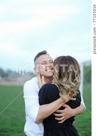 Portrait of young man hugging back view girl on football field. 77103016