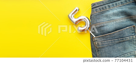 number 5 sticking out of the back pocket of blue jeans on yellow background number 5 sticking out of the back pocket of blue jeans on yellow background 77104431