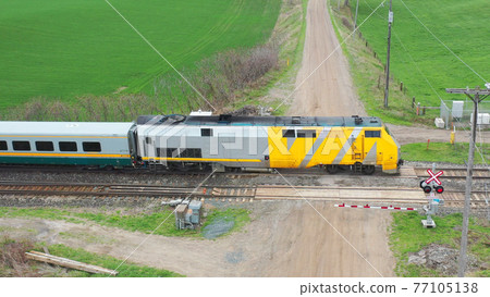 Aerial view of a passenger train crossing a country road 77105138