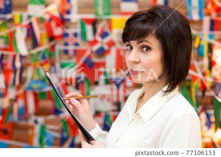 Travel agency manager writes information in a notebook 77106153