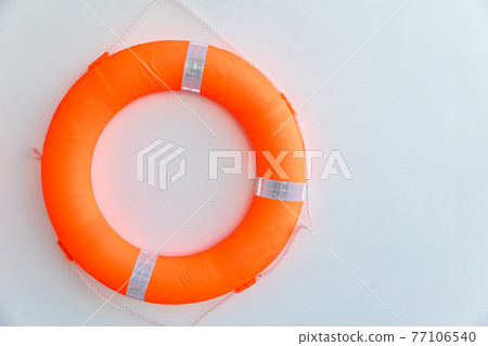 Orange safety torus or lifebuoy hanging on white wall background. Orange safety torus or lifebuoy hanging on white wall background. 77106540