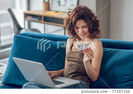 Young pretty woman planning to do some online shopping Young pretty woman planning to do some online shopping 77107188