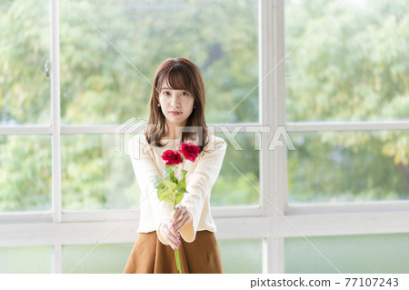 一位年輕女子在窗邊拿著玫瑰表白 77107243