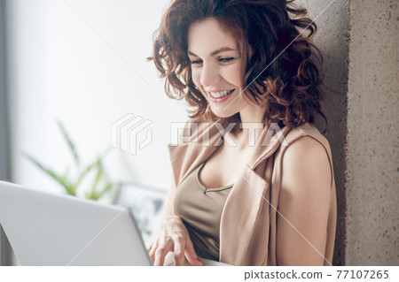 Dark-haired pretty woman working on a laptop and looking concentrated 77107265