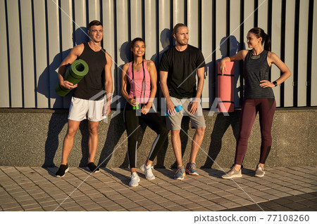 Happy two men and women going to train together in the city Happy two men and women going to train together in the city 77108260