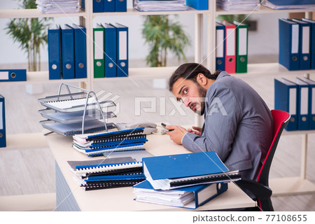 Young male employee unhappy with excessive work in the office 77108655