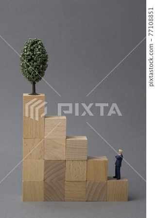 Wooden cube tower and miniature businessman 77108851