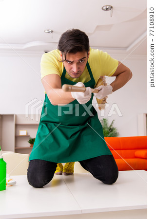 Young male contractor cleaning the house indoors Young male contractor cleaning the house indoors 77108910