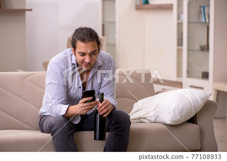 Young drunk man suffering at home 77108933