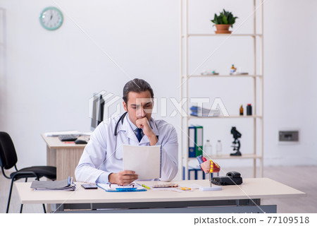 Young male doctor cardiologist working in the clinic Young male doctor cardiologist working in the clinic 77109518