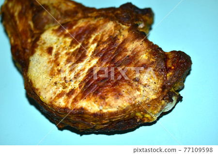 A piece of roast pork close-up on a plate 77109598