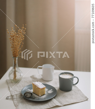 Morning breakfast with a piece of fresh homemade cake, pitcher and cup of coffee on a table Morning breakfast with a piece of fresh homemade cake, pitcher and cup of coffee on a table 77109605