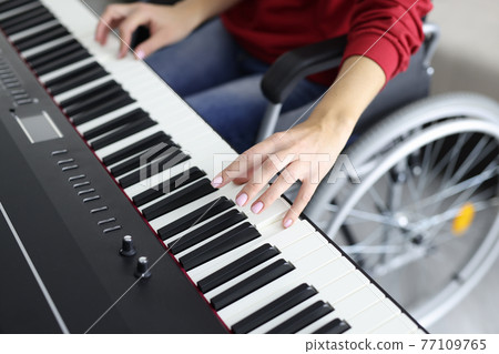 Woman in wheelchair playing synthesizer while making music Woman in wheelchair playing synthesizer while making music 77109765