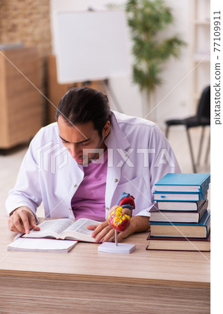 Young male doctor student cardiologist sitting in the classroom Young male doctor student cardiologist sitting in the classroom 77109911
