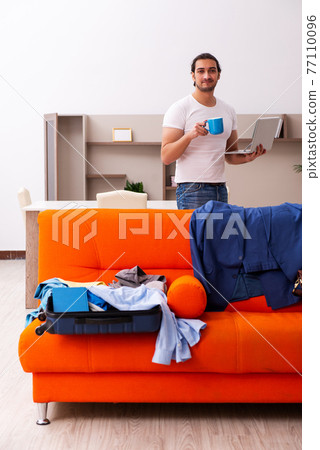 Young man student preparing for trip at home 77110096