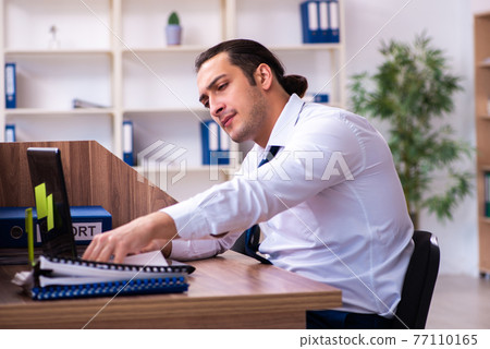 Young male employee unhappy with excessive work in the office 77110165