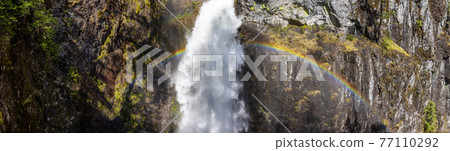 Waterfall rushing down a rocky canyon in the Canadian Mountains. 77110292