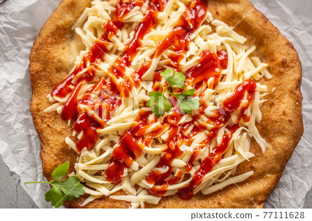 Cheesy hungarian traditional baked langos with Cheesy hungarian traditional baked langos with 77111628