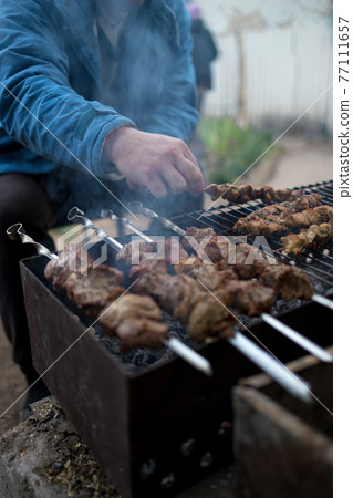 A man prepares on the grill delicious barbecue. shish kebabs on skewers A man prepares on the grill delicious barbecue. shish kebabs on skewers 77111657