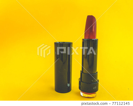 Beautiful fashionable beauty cosmetic glamorous red lipstick for applying makeup on the lips on a yellow gentle background 77112145