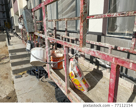 Suspended construction cradle on the background facade of the building. Mobile scaffolding platform for construction work at height, facade cleaning, plastering. Insulation and wall painting, cladding 77112154