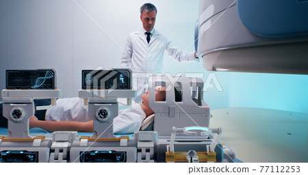 Doctor preparing boy for futuristic MRI procedure Doctor preparing boy for futuristic MRI procedure 77112253