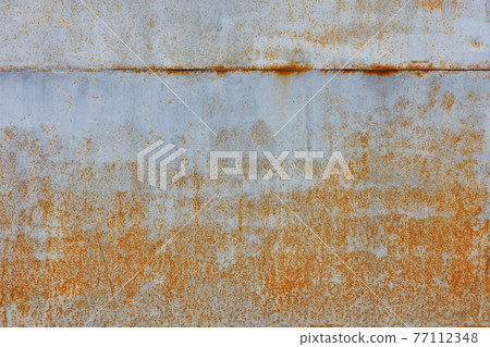 Rust shows through on an old sheet of metal texture painted with gray paint. 77112348