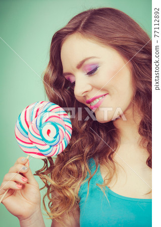Smiling girl with lollipop candy on teal 77112892