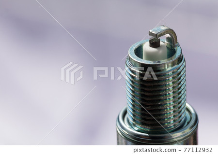 Auto service. New spark plug as spare part of car. 77112932