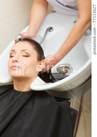 Hairdresser washing her woman customer hair 77113027