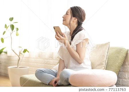 A woman who comes up with something with a smartphone A woman who comes up with something with a smartphone 77113763