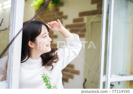 檢查外面天氣的年輕女人 檢查外面天氣的年輕女人 77114595