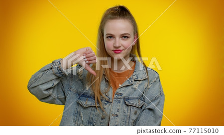 Upset girl in denim jacket showing thumbs down sign gesture, disapproval, dissatisfied, dislike Upset girl in denim jacket showing thumbs down sign gesture, disapproval, dissatisfied, dislike 77115010