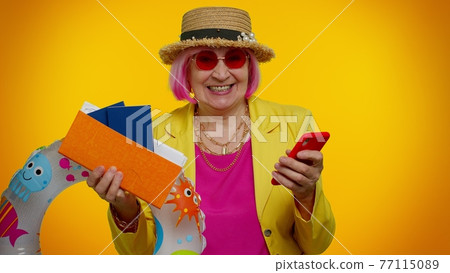 Senior woman grandmother with mobile phone celebrating winning holiday resort vacation tickets pass 77115089