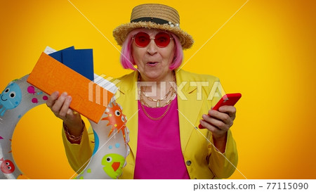 Senior woman grandmother with mobile phone celebrating winning holiday resort vacation tickets pass 77115090