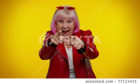 Elderly amused woman pointing finger to camera laughing out loud of ridiculous appearance funny joke 77115435