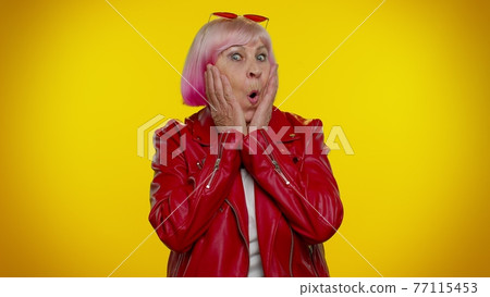 Excited amazed elderly woman raising hands in surprise looking at camera, shocked by sudden victory 77115453
