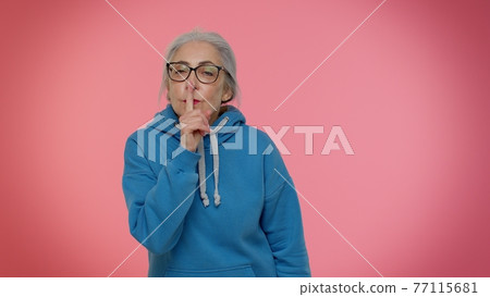 Elderly granny woman presses index finger to lips makes silence gesture sign do not tells secret 77115681