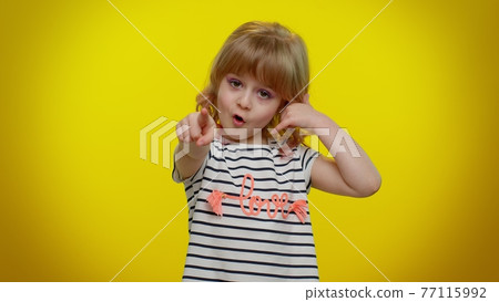 Little cute blonde child girl looking at camera doing phone gesture like says hey you call me back 77115992